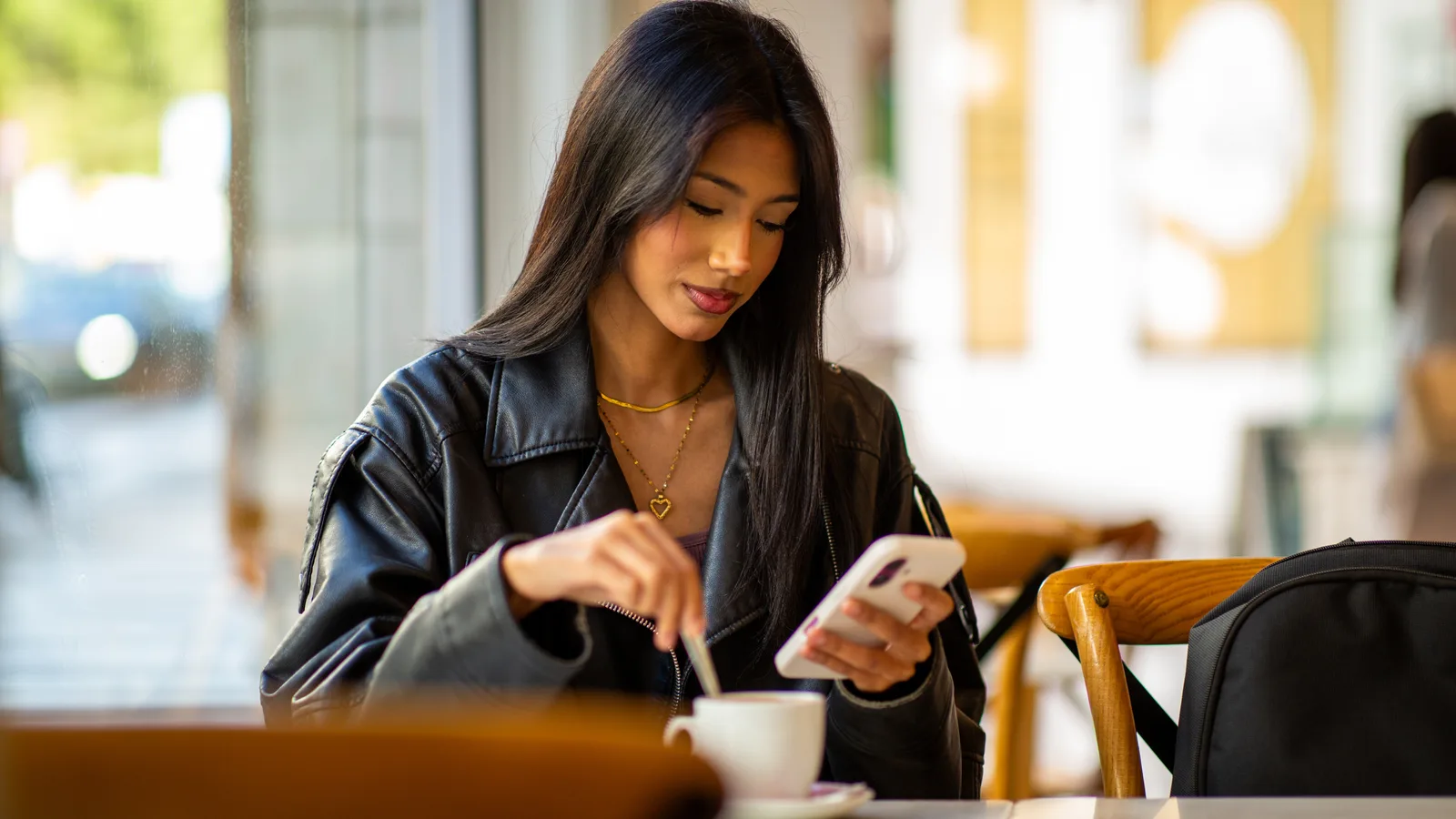 Kund bläddrar i flödet i mobilen på ett café i gyllene ljus, miljön där Instagram-annonsen möter målgruppen