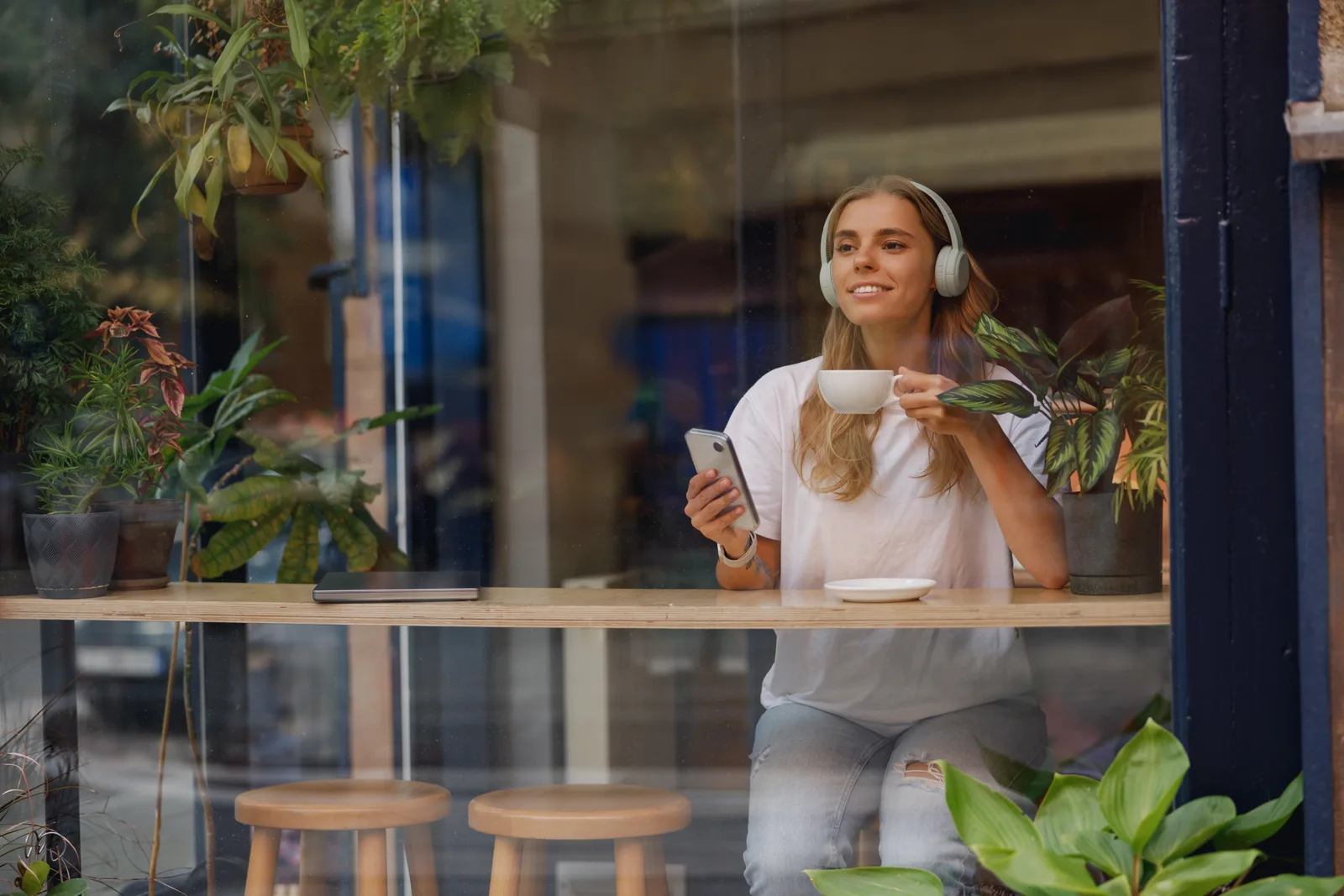 Kund som scrollar flödet i mobilen på ett café, ögonblicket där annonsen möter kunden